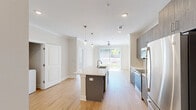 Located at 7630 Knightdale Boulevard in Knightdale, NC, this well-appointed single-floor residence offers a thoughtfully designed layout across a comfortable footprint. Light-toned hardwood-style flooring runs throughout the entire unit, creating a cohesive and clean aesthetic in every room.

The open-concept kitchen serves as the heart of the home, anchored by a central island with a white quartz countertop and an undermount sink, illuminated by globe pendant lights. Sleek gray cabinetry lines the walls, complemented by a white subway tile backsplash and a full suite of stainless steel appliances, including a gas range and refrigerator. A dedicated in-unit laundry area with a full-size washer and dryer is conveniently integrated into the kitchen space.

The living area flows naturally from the kitchen, featuring crown molding, a ceiling fan, and large sliding glass doors that invite abundant natural light and provide access to outdoor views. The generously sized primary bedroom includes a walk-in closet and windows overlooking greenery, while a secondary room offers additional flexibility. The bathroom is designed with accessibility in mind, featuring grab bars, a combination tub and shower, and a gray vanity with a white countertop, all finished with the same warm flooring found throughout.