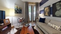 Located at 1000 Central Ave in Charlotte's vibrant Plaza Midwood neighborhood, this one-bedroom, one-bathroom unit offers a thoughtfully designed open-concept layout. Light wood-style flooring runs throughout, creating a cohesive and airy feel.

The kitchen is well-appointed with white shaker cabinetry, granite countertops, subway tile backsplash, and a full suite of stainless steel appliances including a range, microwave, and refrigerator. A peninsula with bar seating provides a casual dining option and seamlessly connects the kitchen to the living area. Pendant and track lighting enhance the space's modern aesthetic.

The living room is defined by a bold navy and white striped accent wall, adding a striking design element. Natural light enters through glass-paneled doors, which also provide outdoor access. The space comfortably accommodates both a seating area and a small dining nook.

The bedroom is a calm retreat with neutral gray walls, a walk-in closet, and a window that brings in natural light. The bathroom continues the design language of the home with a white vanity, granite countertop, a navy accent wall, and a tiled shower-tub combination. Clean lines and brushed nickel fixtures complete the look throughout this well-appointed Charlotte residence.