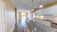 This single-floor residence at 1006 N First St in Wausau, Wisconsin offers a thoughtfully designed layout with contemporary finishes throughout. The kitchen serves as a central highlight, featuring crisp white shaker-style cabinetry, granite countertops, a subway tile backsplash, and a central island with pendant lighting overhead. Stainless steel appliances, including a refrigerator, range, microwave, and dishwasher, complete the well-equipped space. Wood-look flooring flows through the main living areas, complementing the warm, neutral wall tones found throughout.

The living area opens directly to a private balcony through sliding glass doors, offering expansive views of the Wisconsin River and surrounding tree line. Ceiling fans are installed in both the living area and bedrooms, adding comfort and airflow. The bedrooms are carpeted and bathed in natural light through generously sized windows that frame the same scenic waterfront views. A walk-in closet with wire shelving provides organized storage.

The primary bathroom features granite vanity countertops, white cabinetry, and wood-look flooring, while an additional half bath offers convenient functionality. The overall ambiance is clean, bright, and modern, with a strong emphasis on natural light and outdoor views.