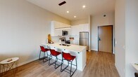 Located at 213 14th Ave SW in Rochester, Minnesota, this contemporary single-floor residence offers a thoughtfully designed open-concept layout with modern finishes throughout. The kitchen is a standout feature, equipped with crisp white shaker cabinetry, a classic subway tile backsplash, stainless steel appliances including a range, microwave, and refrigerator, and a sleek quartz peninsula with bar seating — ideal for casual dining or entertaining. A linear pendant light fixture adds a refined touch above the workspace. The living area flows seamlessly from the kitchen and is bathed in natural light from large floor-to-ceiling windows that frame sweeping city views of downtown Rochester. Light wood-style flooring runs throughout, contributing to a warm, cohesive aesthetic. The bedroom is a tranquil retreat, highlighted by an oversized window with panoramic urban views, exposed concrete architectural accents, and a cozy, well-proportioned layout. The bathroom features light wood-tone flooring, an extended white vanity with ample storage, and a glass-enclosed walk-in shower, delivering a clean and functional design. Overall, the space strikes a balance between contemporary style and everyday practicality in the heart of Rochester.
