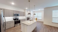 This single-story unit in Houston, TX (77396) presents a well-designed, open-concept floor plan with consistent modern finishes throughout. The kitchen serves as a central highlight, featuring gray shaker-style cabinetry extending to the ceiling for ample storage, light granite countertops, a white subway tile backsplash, and a full suite of stainless steel appliances including a refrigerator with ice maker, electric range, microwave, and dishwasher. A generously sized kitchen island with an integrated sink and pendant lighting overhead provides both additional workspace and a natural connection to the adjoining living area.

The living space is bright and open, benefiting from multiple large windows that allow natural light to fill the room. Wood-look flooring runs throughout the unit, providing a cohesive and easy-to-maintain surface. Ceiling fans are installed in the main living area and bedrooms, enhancing comfort year-round.

The bedrooms are well-proportioned with neutral walls, wood-look floors, ceiling fans, and closet access. The bathrooms are finished to a consistent standard, each featuring gray vanity cabinetry with granite countertops, undermount sinks, large mirrors, and a tub-shower combination with white subway tile surround.