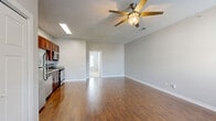 This single-story, one-bedroom, one-bathroom unit is thoughtfully designed to maximize functionality within a compact footprint. The open living area serves as the heart of the space, featuring warm hardwood-style flooring that extends throughout the main areas, neutral gray walls, and a ceiling fan with a light fixture. A window allows natural light to fill the room, contributing to a bright and welcoming ambiance.

The kitchen is positioned adjacent to the living area and is well-equipped with rich dark wood cabinetry, granite countertops, a classic white subway tile backsplash, and a full suite of stainless steel appliances, including an electric range, built-in microwave, dishwasher, and refrigerator. A deep single-basin sink with a flexible pull-down faucet completes the functional workspace.

The bedroom offers plush carpeting, a window for natural light, and a reach-in closet with a full-width hanging rod for storage. The bathroom features tile flooring, a dark-finished vanity with a white basin sink, vanity lighting, and a wall-mounted towel bar. Clean lines and neutral finishes throughout the unit create a cohesive, practical living environment.
