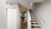 Located at 411 Gregory Dr in Cary, NC, this two-story home offers a practical and well-organized layout across two floors. The main level features a bright living room with rich dark hardwood-style flooring, a ceiling fan, and a pass-through window connecting seamlessly to the kitchen. The kitchen is outfitted with white shaker cabinetry, a mosaic tile backsplash, stainless steel appliances including a refrigerator, range, and over-the-range microwave, plus a skylight that fills the space with natural light. A window overlooking the outdoors adds to the airy feel. A hallway and one of the three bathrooms complete the main floor.

Upstairs, the two carpeted bedrooms offer comfortable retreats. The spacious primary bedroom features neutral tones and a staircase-adjacent entry, while the second bedroom includes dual closets and a window with outdoor views. A third bedroom also features a closet and a window letting in natural light. The bathrooms are clean and functional, with one featuring a full tub-shower combo with brushed nickel fixtures and wood-look flooring. A unique angled bathroom tucks neatly beneath the roofline with a white vanity. Additional built-in cabinetry provides practical storage, complementing the home's efficient design throughout.