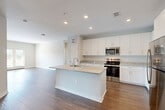 Located at 7105 Hall Rd in Union City, GA, this well-appointed 2-bedroom, 2-bathroom single-story home offers a thoughtfully designed open-concept layout. The combined dining room, kitchen, and living area forms the heart of the home, anchored by a stylish kitchen featuring a central island with granite countertops, a deep basin sink, crisp white shaker cabinetry, stainless steel appliances including a range, microwave, and refrigerator, and recessed lighting overhead. Rich wood-style flooring flows seamlessly throughout the entire home, adding warmth and continuity to each space. Both bedrooms are generously sized, bathed in natural light through large windows with blinds, and include ceiling fans for added comfort. The primary bedroom offers a spacious walk-in closet with wire shelving, providing ample storage. Additional closets are found throughout the home, complemented by a dedicated pantry, laundry room, and utility room. The bathrooms are finished with granite-topped vanities and full tub-shower combinations. Neutral gray tones on the walls, clean white trim, and an abundance of natural light create a bright, modern ambiance throughout this move-in-ready home.