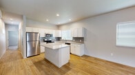 Located at 966 Brant Hollow Ct in Colorado Springs, Colorado, this single-story home offers a clean, contemporary design with a neutral color palette and quality finishes throughout. The kitchen serves as a central highlight, showcasing white shaker-style cabinetry, granite countertops with subtle veining, and a grey subway tile backsplash. A central island provides additional prep space and casual seating, while stainless steel appliances — including a refrigerator, range, microwave, and dishwasher — complete the well-appointed setup. Recessed lighting illuminates the space, and light hardwood flooring extends throughout the main living areas, lending warmth and continuity. A wall-mounted mini-split unit offers efficient climate control. The bedrooms feature plush neutral carpeting, bright windows with blinds, and closet access, creating comfortable, functional retreats. One bedroom includes a walk-in closet area and windows that allow for natural light. The bathroom is outfitted with a full tub-shower combination, clean white finishes, and matching hardwood-style flooring. Overall, the home presents a bright, move-in-ready interior with a cohesive modern aesthetic suited for everyday comfort.