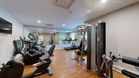Located at 10810 Rail Way in Lone Tree, CO, this fitness center is a well-appointed, single-room exercise facility designed to support a comprehensive workout routine. The space features warm hardwood flooring throughout, neutral gray walls, and recessed lighting that creates a clean, energizing atmosphere.

The room is outfitted with a variety of Spirit-brand cardio equipment, including treadmills, elliptical trainers, and both upright and recumbent stationary bikes, catering to a range of fitness preferences. Strength training is supported by a multi-function cable machine and a dedicated leg extension/curl station, providing options for both upper and lower body conditioning. A wall-mounted flat-screen television adds an entertainment element for users during workouts.

A full wall of mirrors along one side of the room visually expands the space and allows users to monitor their form during exercise. The layout is thoughtfully organized to maximize usable floor area while maintaining comfortable movement between stations. HVAC vents are integrated into the ceiling, ensuring proper climate control. A dedicated entry door with a windowed panel provides access to the facility. The overall design is functional, modern, and well-maintained, making it a practical fitness resource for residents of the Lone Tree community.