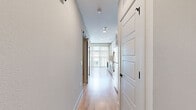 Located at 612 N Zang Blvd in Dallas, TX, this one-bedroom, one-bathroom unit offers a thoughtfully designed layout that maximizes every square foot of its compact footprint. The open-concept kitchen and living area serves as the heart of the home, showcasing light wood-style flooring, recessed lighting, and large floor-to-ceiling windows dressed with vertical blinds that flood the space with natural light and offer outdoor views. The kitchen is outfitted with two-tone cabinetry — crisp white upper cabinets paired with slate-gray lower drawers — accented by brushed gold hardware. White subway tile backsplash, quartz countertops, stainless steel appliances, and a gold-tone sink faucet complete the polished, contemporary aesthetic. A sleek barn-style door adds a stylish architectural touch along the hallway leading to the private spaces. The bedroom features warm neutral tones, plush carpet flooring, a ceiling fan with lighting, and a window allowing natural light. The bathroom continues the refined design language with a gray vanity, quartz countertop, gold fixtures, a large framed mirror, and classic penny tile flooring. A dedicated closet provides practical storage, rounding out this well-appointed urban residence.