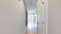 Located at 612 N Zang Blvd in Dallas, TX, this one-bedroom, one-bathroom unit offers a thoughtfully designed layout that maximizes every square foot of its compact footprint. The open-concept kitchen and living area serves as the heart of the home, showcasing light wood-style flooring, recessed lighting, and large floor-to-ceiling windows dressed with vertical blinds that flood the space with natural light and offer outdoor views. The kitchen is outfitted with two-tone cabinetry — crisp white upper cabinets paired with slate-gray lower drawers — accented by brushed gold hardware. White subway tile backsplash, quartz countertops, stainless steel appliances, and a gold-tone sink faucet complete the polished, contemporary aesthetic. A sleek barn-style door adds a stylish architectural touch along the hallway leading to the private spaces. The bedroom features warm neutral tones, plush carpet flooring, a ceiling fan with lighting, and a window allowing natural light. The bathroom continues the refined design language with a gray vanity, quartz countertop, gold fixtures, a large framed mirror, and classic penny tile flooring. A dedicated closet provides practical storage, rounding out this well-appointed urban residence.