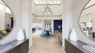 This generously sized single-floor amenity center offers a well-rounded selection of community spaces designed for both relaxation and recreation. The grand entrance lobby immediately impresses with soaring double-height ceilings, clerestory windows that flood the space with natural light, polished concrete floors, and a striking orb chandelier suspended above a central round table. Accent walls in deep navy blue lend a sophisticated contrast to the crisp white walls throughout.

The lounge area features expansive floor-to-ceiling sliding glass doors that open to an outdoor terrace, offering seamless indoor-outdoor living with views of the surrounding grounds. Plush seating arrangements and a wall-mounted TV make this an inviting gathering space.

The fitness center is a standout feature, divided into dedicated cardio and strength training zones. The cardio area is lined with treadmills, ellipticals, and stationary bikes alongside full-length mirrors and teal accent walls, while the strength zone is equipped with Precor cable machines, free weights, and functional training equipment—all bathed in natural light from large windows.

A game and social lounge rounds out the amenities, complete with a pool table, high-top seating, a mounted TV, and a fully equipped kitchenette featuring stainless steel appliances, mosaic tile backsplash, and ample cabinetry—ideal for community gatherings.