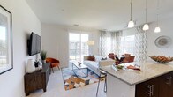 This single-floor residence offers a thoughtfully designed open-concept layout that seamlessly connects the kitchen, dining, and living areas into one cohesive and functional living space. The kitchen features elegant granite countertops with a breakfast bar that provides casual seating and flows naturally into the main living area, making it ideal for both everyday living and entertaining.

The living room is generously proportioned and filled with natural light, thanks to large floor-to-ceiling windows and a sliding glass door that leads to an outdoor balcony. The bright, neutral color palette of white walls and light carpeting is accented by warm furnishings in rich amber and burnt orange tones, creating a welcoming and contemporary ambiance.

Adjacent to the living area, a dedicated dining space is illuminated by a stylish pendant light, offering a comfortable setting for meals. The sliding glass door and expansive windows throughout provide views of the surrounding exterior, further enhancing the sense of openness and connectivity to the outdoors.

Throughout the space, clean lines and modern finishes define the aesthetic, while the open floor plan ensures an effortless flow between each area. The abundance of natural light and thoughtful layout make this a bright, airy, and highly livable residence.