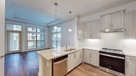 This well-appointed single-floor residence at 2925 Buford Dr in Buford, Georgia, offers a thoughtfully designed open-concept layout filled with modern finishes and abundant natural light. The kitchen serves as a central highlight, featuring gray shaker-style cabinetry, granite countertops, a hexagonal tile backsplash, and a peninsula with an undermount sink and built-in dishwasher. Stainless steel appliances — including a range, microwave, and side-by-side refrigerator — complete the space, while pendant lighting adds a refined touch overhead. A tray ceiling with crown molding defines the adjoining living area, which is anchored by warm hardwood-style flooring and large windows that frame outdoor views and invite generous natural light. The bedroom offers plush carpeting, a ceiling fan, and windows on multiple sides, creating a bright and comfortable retreat. The bathroom is finished with large-format tile flooring, a floating vanity with a framed mirror, and an open walk-in shower outfitted with full-height tile surround and a handheld showerhead — thoughtfully designed for accessibility. Together, these spaces deliver a clean, contemporary aesthetic with practical, high-quality finishes throughout.