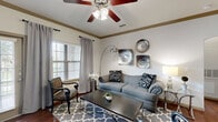 Located along Highway 105 in Montgomery, TX, this single-floor, one-bedroom, one-bathroom residence offers a thoughtfully designed layout that maximizes both function and comfort. The open-concept kitchen and living area serves as the heart of the home, anchored by rich hardwood-style flooring that flows throughout the main spaces. The kitchen is equipped with dark espresso cabinetry, granite-style countertops, stainless steel appliances including a full-size refrigerator, a deep double-basin sink, subway tile backsplash, and a peninsula with pendant lighting and bar seating — ideal for casual dining or entertaining. The living room features elegant crown molding, a ceiling fan, and multiple windows that invite natural light, creating a bright and welcoming atmosphere. The bedroom is a comfortable retreat with plush carpeting, dual windows with views of the surrounding greenery, a ceiling fan, and direct access to a closet. The full bathroom offers a tub-shower combination with tiled surround, dark wood vanity with a white countertop, and hardwood-style flooring. A dedicated laundry area with wire shelving adds everyday convenience. The entrance and hallway provide a smooth transition between all areas of this well-organized, efficiently planned residence.