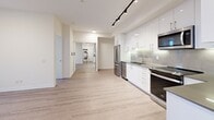 Located at 2215 Sheridan Park Drive in Mississauga, this well-appointed one-bedroom, one-bathroom unit offers a thoughtfully designed open-concept layout with modern finishes throughout. Light-toned laminate flooring runs continuously through the living spaces, complementing the bright white walls and recessed lighting that contribute to a clean, contemporary aesthetic.

The kitchen is a standout feature, outfitted with sleek, high-gloss white cabinetry extending to the ceiling, dark countertops, a tile backsplash, and a full suite of stainless steel appliances including a refrigerator, dishwasher, electric range, and built-in microwave. Track lighting overhead adds both style and functionality. The kitchen flows seamlessly into the open living area, creating an ideal space for everyday living and entertaining.

The bedroom is a comfortable, quiet retreat featuring a sliding-door closet and large floor-to-ceiling sliding glass doors that open directly onto the private balcony. The balcony offers sweeping panoramic views of the surrounding Mississauga skyline and cityscape. The full bathroom is finished with clean white tile, a soaker tub with a handheld shower, and warm wood-toned cabinetry. An in-unit laundry area adds everyday convenience to this well-rounded urban residence.