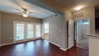 Located at 2752 Gaston Ave in Dallas, Texas, this single-floor unit offers a well-designed layout with a cohesive blend of modern finishes and functional living spaces. Rich, dark hardwood flooring runs throughout the main living areas, providing a warm and polished aesthetic.

The open living area is bright and airy, highlighted by French doors that flood the space with natural light and offer views of the surrounding greenery and access to a private balcony. A ceiling fan adds comfort overhead. Track lighting accents the transition into the kitchen area, which features a breakfast bar peninsula, dark espresso cabinetry, granite countertops, and stainless steel appliances including a refrigerator, range, microwave, and dishwasher — all arranged in a practical galley-style configuration.

The bedrooms are carpeted for comfort, each with ceiling fans and windows that bring in natural light. One bedroom includes a walk-in closet with built-in shelving. The bathroom is outfitted with a full tub-shower combination with white tile surround. A dedicated utility area houses a water heater and includes washer/dryer hookups, adding everyday convenience. Neutral gray walls throughout the unit create a versatile backdrop suitable for a variety of interior styles.