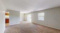 This single-floor home on Queen Anne Drive in Evansville, Indiana, offers a straightforward and functional layout designed for comfortable everyday living. The living area is generously sized, featuring neutral-toned carpet throughout and soft, light-colored walls that create a clean, open atmosphere. A pendant light fixture anchors the space, while a sliding glass door provides direct access to the outdoors, allowing natural light to filter into the room. An adjacent window with blinds further brightens the interior.

The kitchen is equipped with warm-toned wood cabinetry extending to the upper and lower sections of the walls, offering ample storage. A double stainless steel sink, laminate countertops, and tile flooring complete the functional workspace, with black appliances including a refrigerator and dishwasher integrated into the design.

The bedrooms are carpeted and neutrally painted, each featuring windows with blinds that admit natural light while maintaining privacy. The rooms provide comfortable dimensions suitable for standard furnishings. The bathroom includes a tub and shower combination with chrome fixtures set against a clean, white surround.

Overall, the home presents a practical and move-in ready interior with consistent finishes, neutral tones, and convenient outdoor access.
