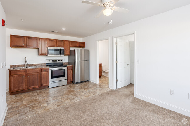 Carpeted living room towards kitchen. - Hemingway Apartments