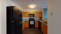 This single-floor residence in Worcester, Massachusetts offers a thoughtfully designed layout that balances functionality and comfort throughout its living spaces. The kitchen is equipped with warm honey-toned cabinetry, granite-style countertops, dark hardwood flooring, and black appliances including a range, over-the-range microwave, and refrigerator. A breakfast bar with pendant lighting connects the kitchen to the adjacent living and dining area, creating an open, sociable flow.

The living room is a standout space, featuring a distinctive teal accent wall, large bay windows that flood the room with natural light, and plush carpeting. A secondary flex room with a window overlooking greenery provides an ideal space for a home office or sitting area.

The bedrooms are generously sized with soft carpeting and ample natural light. One bedroom includes direct access to a private bathroom and a walk-in closet, while a second bedroom connects to its own en-suite bath. Both bathrooms feature clean white cabinetry, tile flooring, large mirrors, and tub-shower combinations. The overall aesthetic is modern and cohesive, with neutral tones accented by pops of color throughout.