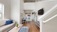 This contemporary 990 square foot apartment in College Station, TX, is a well-designed two-story living space. The interior boasts 2 bedrooms and 2 bathrooms, with the primary bedroom measuring 110 square feet. The ground floor spans 570 square feet, while the upper level covers 420 square feet.

The apartment features an open-concept living area with soaring ceilings and large windows that flood the space with natural light. The living room seamlessly connects to a dining area, creating an ideal space for entertaining or relaxation. Hardwood floors run throughout, adding warmth and elegance to the interior.

The kitchen, while compact, is efficiently designed with white cabinetry and modern appliances. Both bathrooms are tastefully appointed, featuring clean lines and contemporary fixtures. The bedrooms are comfortably sized, with the second bedroom potentially doubling as a home office or guest room.

Additional amenities include a laundry area and ample closet space. The apartment's decor is neutral and modern, with pops of color in the furnishings and artwork. The overall ambiance is one of comfort and functionality, making it an ideal living space for young professionals or small families.