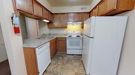 This upgraded two-bedroom, one-bathroom residence in Ypsilanti, Michigan, offers a practical and comfortable single-floor layout with generous living space. The kitchen is well-appointed with warm medium-toned wood cabinetry extending to the upper walls, providing abundant storage. Granite-style countertops complement the full suite of white appliances, including a dishwasher, electric range with overhead ventilation, and a full-sized refrigerator. Stone-look tile flooring completes the kitchen's functional aesthetic.

The living area features neutral-toned carpeting and a ceiling fan, creating a comfortable environment. A built-in closet with shelving is conveniently positioned near the entry. Both bedrooms are generously proportioned with soft carpeting and windows that allow natural light and outdoor views of the surrounding landscape. Each bedroom features a textured ceiling and ample wall space for furnishings.

The full bathroom is notably well-equipped, featuring an elongated dual-sink vanity with granite-style countertops, warm wood cabinetry beneath, and mirrored medicine cabinets above each sink. Stone-look tile flooring ties the bathroom together cohesively. The overall interior palette of neutral tones throughout creates a clean, move-in-ready atmosphere.