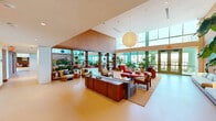 Located at 777 North Central Avenue in the heart of Phoenix, AZ, this striking single-floor space offers an impressive open-plan layout that unfolds across a generous footprint. Soaring double-height ceilings and expansive floor-to-ceiling windows define the architecture, flooding the interior with abundant natural light and framing panoramic views of the surrounding Phoenix skyline.

The space is organized into a series of distinct yet interconnected living areas, each thoughtfully furnished and styled. Seating vignettes feature a curated mix of mid-century-inspired chairs and sofas in warm tones—rich reds, deep oranges, and soft pinks—anchored by area rugs and low wood coffee tables. A standout sunken lounge area is clad in terracotta brick tile, fitted with built-in upholstered seating and a large wall-mounted screen, offering an intimate retreat within the broader open space.

A communal dining area features a long natural wood table beneath a sculptural layered wood pendant light, adjacent to glass doors that open onto an outdoor terrace with city views. Lush indoor plants are woven throughout, softening the architecture and adding vibrancy. Bold, large-scale artwork adorns select walls, contributing to a gallery-like cultural ambiance. Built-in bookshelves further enrich the space, completing a sophisticated and welcoming environment.