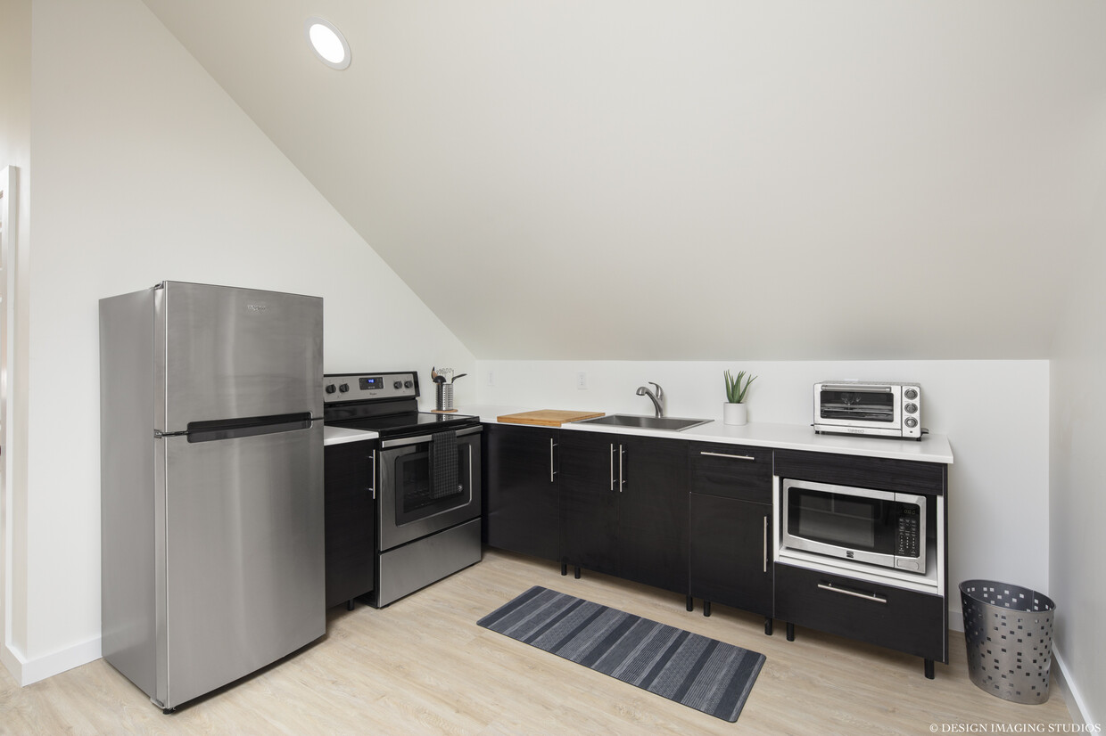 The kitchen features an electric stove, fridge, microwave. - 181 Peace St