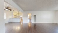 Located at 11942 Old River School Rd in Downey, CA, this single-story, 3-bedroom, 2-bathroom home offers a well-organized layout across a comfortable footprint. The open living and dining area is anchored by rich, dark hardwood flooring and a large horizontal window that fills the space with natural light. A textured ceiling adds classic character throughout the main living areas. The kitchen flows seamlessly from the dining space and features white cabinetry, a granite-style countertop, a peninsula with bar-style pendant lighting, and tile flooring — providing both functionality and style. Abundant storage is a hallmark of this home, with seven closets distributed throughout, including sliding-door and built-in closet options in the bedrooms. Each of the three bedrooms is carpeted for comfort and equipped with a ceiling fan; bedrooms are bright thanks to horizontal windows with views of surrounding greenery. The primary bedroom includes multiple closet spaces. Both bathrooms are finished with tile flooring, white vanities with granite-style countertops, and clean white surrounds — one features a shower/tub combo with a window, and the other includes a standalone shower. A dedicated utility/laundry area with white upper and lower cabinetry and tile flooring rounds out this well-appointed home.