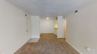 This single-story unit offers a practical and comfortable floor plan designed to maximize functionality. The entry opens into a spacious living area finished with neutral-toned wall-to-wall carpeting and a textured ceiling. A ceiling fan overhead provides air circulation, while the open layout allows for flexible furniture arrangement. Tile flooring marks the entryway, creating a clean transition from the front door into the main living space.

The kitchen is positioned adjacent to the living area and features warm wood-toned cabinetry, both upper and lower, offering ample storage. A double-basin stainless steel sink, light-colored countertops, and a full-size refrigerator complete the kitchen's functional setup. Tile flooring runs throughout this area for easy maintenance.

The bedroom is generously proportioned, featuring plush carpeting, a ceiling fan with light fixture, and a window that allows natural light to filter in, creating a bright and comfortable retreat.

The bathroom includes a single-sink vanity with wood cabinetry, a wide mirror with overhead lighting, a full-size soaking tub with shower, and tile flooring throughout. The layout is clean and efficient, offering all essential amenities in a well-organized space.