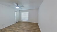 This efficiently designed single-story unit offers a practical and well-organized layout comprising a living room, bedroom, kitchen, bathroom, and closet. The living room serves as the entry point, featuring wood-look plank flooring, crisp white walls, and a ceiling fan with integrated lighting. A window fitted with horizontal blinds allows natural light to fill the space, contributing to a bright and clean atmosphere.

The kitchen is accessible from the living area and is equipped with white cabinetry extending to the upper walls, a stainless steel refrigerator, and a single-basin sink with a modern faucet. The wood-look flooring continues seamlessly through this area, maintaining a cohesive aesthetic.

The bedroom is a comfortable, carpet-floored room with its own ceiling fan and a window with blinds that provides natural light. A closet is accessible from the bedroom corridor, offering dedicated storage space.

The bathroom is finished in an all-white palette, featuring a tub-shower combination with tiled surround, a toilet, a vanity with a single sink, and wood-look flooring. The overall ambiance of the unit is clean, neutral, and move-in ready.