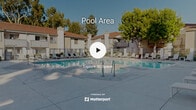 Located at 1500 Shadowridge Dr in Vista, California, this two-story residential community showcases a thoughtfully designed outdoor amenity area that serves as its central gathering space. The architecture follows a Spanish-influenced style, characterized by red clay tile roofing, light stucco exteriors, and warm wood-trimmed accents that lend a cohesive, resort-like aesthetic throughout the property.

At the heart of the outdoor space is a generously sized swimming pool with clear, blue-tinted water, complemented by an adjacent circular spa. The expansive concrete pool deck is furnished with rows of white lounge chairs and chaise lounges, providing ample space for relaxation under the Southern California sun. Shaded seating areas with umbrellas and tables offer additional comfort for outdoor dining or socializing.

The surrounding two-story residential buildings frame the courtyard, creating an enclosed yet open-air atmosphere. Lush mature trees, including a prominent shade tree at the center of the complex, add natural greenery and visual depth to the setting. A dedicated clubhouse or pool facility building with a red tile roof is positioned directly adjacent to the pool and spa, featuring locker rooms or restroom access for residents. The overall ambiance is bright, clean, and inviting, well-suited to the warm Southern California climate.