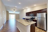 Located in Ankeny, Iowa, this well-designed 2-bedroom, 2-bathroom single-story home offers a comfortable and functional layout. The open-concept living area is immediately welcoming, featuring vaulted ceilings, recessed lighting, and rich hardwood-style flooring that flows seamlessly from the kitchen through to the living room. A ceiling fan adds both style and comfort to the expansive living space, which is bathed in natural light from large sliding glass doors. The kitchen is a standout, anchored by a granite-topped island with a built-in sink, dark espresso cabinetry, and a full suite of stainless steel appliances including a refrigerator, electric range, and microwave. A pantry provides convenient additional storage. Both bedrooms are carpeted and feature ceiling fans, natural light from large windows, and generous closet space, including a walk-in closet with wire shelving in the primary bedroom. The two bathrooms are finished with matching dark cabinetry and granite countertops, with one featuring a walk-in shower and wood-look flooring. Additional highlights include a utility room, multiple closets throughout, and a spacious attached two-car garage with an automatic opener, completing this practical and polished home.
