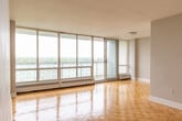 Located at 1501 Woodbine Ave in Toronto, this well-appointed one-bedroom, one-bathroom unit offers a functional and comfortable layout across a single floor. The living room is a standout space, featuring classic parquet wood flooring that extends throughout the unit and a full wall of floor-to-ceiling windows with a sliding door that opens to a balcony, flooding the room with natural light and offering expansive treetop views. The open sightlines create an airy, bright atmosphere ideal for everyday living. The kitchen has been thoughtfully updated with sleek white shaker-style cabinetry, grey quartz countertops, a grey glass tile backsplash, stainless steel sink, and modern appliances including a dishwasher, all set on neutral large-format tile flooring. The bedroom is a comfortable size, equipped with mirrored sliding closet doors and a window that frames serene green views, complemented by baseboard heating. The bathroom features a clean, contemporary design with a soaker tub and shower combination, white subway tile surround with a mosaic accent border, and coordinating quartz countertops. Neutral tones and consistent finishes throughout give the unit a cohesive, move-in-ready feel.
