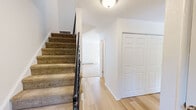 Located at 50 Rinaldi Blvd in Poughkeepsie, NY, this two-story residence offers three bedrooms and three bathrooms across two well-proportioned floors. The main level features light hardwood-style flooring throughout the kitchen, hallway, and bathroom, creating a clean, cohesive look. The galley-style kitchen is outfitted with warm honey-toned cabinetry, granite-look countertops, and stainless steel appliances including a dishwasher, range, and refrigerator. A bright living room with plush carpeting leads to a private balcony through sliding glass doors, flooding the space with natural light and outdoor views. A convenient half bath with a white vanity and wood-framed mirror completes the main floor. Upstairs, the generously sized primary bedroom stands out with dual closets, large windows that invite abundant natural light, and plush carpeting underfoot. Two additional bedrooms share access to well-appointed bathrooms, including one featuring a wide white vanity with a medicine cabinet mirror and classic tile flooring. A carpeted staircase with a black metal railing connects the two floors, adding a touch of contrast to the home's bright, neutral palette. The upper hallway offers additional closet storage, rounding out a thoughtfully designed and functional layout.