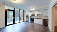 Located at 1400 W Peachtree St NW in Atlanta's Midtown neighborhood, this thoughtfully designed single-floor unit offers a clean, contemporary aesthetic throughout. Rich hardwood-style flooring runs continuously through the main living areas and hallways, complementing the bright white walls and modern finishes that define the space.

The open-concept kitchen is a standout feature, outfitted with sleek white cabinetry, a subtle tile backsplash, dark countertops, and a full suite of stainless steel appliances including a gas range, microwave, refrigerator, and dishwasher. Track lighting overhead adds a functional yet stylish touch. Floor-to-ceiling sliding glass doors open directly to a private balcony, allowing natural light to pour into the living area and providing outdoor views of the surrounding urban streetscape.

The hallways connect the living space to the private quarters, maintaining a clean and uncluttered flow. The bathroom features crisp white marble-style tile flooring and is positioned adjacent to a dedicated in-unit laundry closet with a stacked washer and dryer — a practical and convenient amenity. Additional rooms offer flexible, open layouts with neutral walls and recessed lighting, ready to be configured to suit a variety of needs. The overall ambiance is modern, minimalist, and move-in ready.
