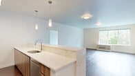 This well-appointed 2-bedroom, 2-bathroom residence at 22 Sussex Street in Hackensack, NJ offers a thoughtfully designed layout with modern finishes throughout. Dark hardwood flooring flows consistently across the entire space, complementing the clean white walls and creating a warm yet contemporary aesthetic.

The open-concept kitchen and living area serves as the heart of the home. The kitchen features white cabinetry, stainless steel appliances including a French door refrigerator, gas range, and built-in microwave, as well as a tile backsplash and a large peninsula with light-toned countertops and stylish pendant lighting overhead.

Both bedrooms are generously sized, with large windows that frame lush, tree-lined views and allow abundant natural light to fill the rooms. The spacious primary bedroom includes a walk-in closet outfitted with built-in shelving and hanging rods for ample storage.

The two bathrooms showcase modern design with distinctive pebble-tile flooring. The primary bathroom offers a sleek walk-in shower with floor-to-ceiling wood-toned tile and a frameless sliding glass door, a floating vanity, and open shelving. The second bathroom features a soaking tub with a tiled surround, a floating vanity, and a backlit mirror. A dedicated hallway provides easy access to all rooms, completing this well-organized and stylish residence.