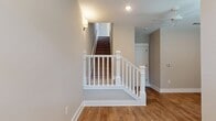This three-story residence offers a generous 1610 square feet of living space, thoughtfully distributed across multiple levels. The ground floor encompasses 260 square feet, while the first and second floors provide 680 and 670 square feet respectively. The home boasts two bedrooms, including a spacious 210-square-foot primary suite, and an impressive four bathrooms, ensuring ample privacy and convenience for residents and guests alike.

The interior layout includes essential spaces such as two closets, a hallway, and a staircase connecting the floors. A notable feature is the combined kitchen and living room area, complemented by an additional separate living room, offering versatile spaces for both daily life and entertaining.

The image showcases a portion of the interior, revealing warm wood flooring that adds a touch of natural elegance. A striking white staircase with a sturdy banister serves as a focal point, leading to upper levels. The walls are painted in a neutral tone, creating a bright and airy atmosphere enhanced by recessed lighting and a stylish wall sconce. Crown molding adds a refined touch to the space, while the open area suggests potential for flexible furniture arrangement and personalization.
