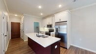 This well-appointed single-story home in Jonesboro, Arkansas offers a thoughtfully designed layout across three bedrooms and two full bathrooms. Warm wood-look flooring flows consistently throughout the entire home, creating a cohesive and inviting aesthetic.

The kitchen serves as a functional centerpiece, featuring white shaker-style cabinetry with matte black hardware, a contrasting dark-base island with a white quartz countertop and double undermount sink, and a full suite of stainless steel appliances including a French door refrigerator with ice maker, electric range, and built-in microwave. Crown molding adds a refined touch overhead.

The open living area is bright and airy, benefiting from recessed lighting, crown molding, and natural light through sizable windows with blinds. A glass-panel door provides access to the exterior.

The bedrooms are comfortably sized, each featuring ceiling fans with light kits and neutral gray walls. Multiple bedrooms offer natural light through windows with blinds, enhancing the sense of openness.

Both bathrooms are finished with white vanity cabinetry, matte black hardware, and dark-framed mirrors. One bathroom includes a tub-shower combination with white surround, while the other features an elongated vanity with ample storage. Wood-look flooring carries through both bathrooms for a consistent, modern look.