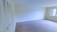 This single-floor space presents a straightforward and functional layout with a distinctly utilitarian character. The interior is defined by painted concrete block walls finished in a crisp white, lending the space a clean, bright aesthetic while highlighting its solid, durable construction. The walls' textured masonry surface adds a subtle visual depth to the otherwise minimal design.

The flooring throughout is covered in neutral-toned carpet, providing a soft contrast to the hard masonry walls and contributing to a quiet, understated ambiance. The open layout offers flexibility, making the space adaptable to a variety of uses.

Smooth, painted drywall ceilings complement the white-painted block walls, maintaining a cohesive and uncluttered appearance throughout. The absence of built-in fixtures or furnishings means the space is presented as a blank canvas, well-suited for those looking to configure it according to their specific needs. Overall, the space combines durable construction materials with a clean, open interior that is practical and easy to maintain.