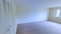 This single-floor space presents a straightforward and functional layout with a distinctly utilitarian character. The interior is defined by painted concrete block walls finished in a crisp white, lending the space a clean, bright aesthetic while highlighting its solid, durable construction. The walls' textured masonry surface adds a subtle visual depth to the otherwise minimal design.

The flooring throughout is covered in neutral-toned carpet, providing a soft contrast to the hard masonry walls and contributing to a quiet, understated ambiance. The open layout offers flexibility, making the space adaptable to a variety of uses.

Smooth, painted drywall ceilings complement the white-painted block walls, maintaining a cohesive and uncluttered appearance throughout. The absence of built-in fixtures or furnishings means the space is presented as a blank canvas, well-suited for those looking to configure it according to their specific needs. Overall, the space combines durable construction materials with a clean, open interior that is practical and easy to maintain.