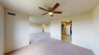 This single-floor unit offers a functional and straightforward layout across several well-defined spaces. The living area is generously sized, finished with neutral wall-to-wall carpeting and warm beige walls that create a bright, open atmosphere. A ceiling fan with a light fixture is centrally mounted overhead, providing both airflow and ambient lighting. The open layout connects visually to the kitchen and additional rooms, lending the space a cohesive, airy feel. Large windows in the bedroom area invite natural light and offer views of surrounding greenery.

The kitchen is equipped with bold dark cabinetry that contrasts with lighter countertops and a tile-pattern vinyl floor. White appliances, including a gas range, refrigerator, and dishwasher, are included. A built-in pantry with shelving provides additional storage directly adjacent to the kitchen.

The bedroom is a comfortable, carpeted room featuring a walk-in closet with interior shelving. The bathrooms feature classic white tile wainscoting, mosaic tile flooring, and a streamlined vanity with a countertop sink and mirror. The overall ambiance of the unit is clean, neutral, and move-in ready, offering a practical living environment.