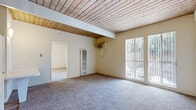 Located in Lakeside, CA, this single-story, one-bedroom, one-bathroom unit offers a compact yet functional layout across its single floor. A defining architectural feature throughout the space is the warm, natural wood-plank ceiling, which adds character and a distinct visual element to each room.

The living room is comfortably sized, with plush carpeting, a wall-mounted air conditioning unit for climate control, and a large sliding glass door that fills the space with natural light and provides views of the outdoors. A built-in wall heater adds additional climate versatility.

The bedroom is generously proportioned, occupying a substantial portion of the overall footprint. It features the same wood-plank ceiling, soft carpeting, a large sliding closet with built-in shelving, and a window that lets in natural light.

The kitchen is efficiently designed with white cabinetry above and below the countertop, a single-basin sink, a gas range with overhead ventilation hood, and wood-style flooring — offering a clean, functional workspace.

The bathroom includes a full tub-shower combo with white tile surround, a toilet, and a towel bar, maintaining a clean and straightforward design.

Overall, the unit presents a consistent aesthetic with neutral tones, wood-accented ceilings, and practical amenities suited for comfortable everyday living.