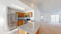 Located at 1009 Beryl Way in Watervliet, NY, this 2-bedroom, 4-bathroom single-floor home offers a well-designed layout with comfortable living spaces throughout. The open-concept kitchen is a standout feature, equipped with stainless steel appliances — including a refrigerator, electric range, and microwave — warm oak cabinetry, and a granite-topped island with a built-in sink. Soaring vaulted ceilings extend from the kitchen into the adjacent living area, which is brightened by natural light streaming through large windows. The spacious primary bedroom features a tray ceiling, plush carpeting, a triple window overlooking mature trees, and direct access to a closet and en-suite bathroom. Additional bedrooms are similarly carpeted and well-proportioned. The four bathrooms are finished with clean white tile flooring and tub-shower combinations. A dedicated laundry room houses a full-size washer and dryer with built-in shelving above. The hallway bathroom includes an oak vanity with granite countertop, a large mirror, and tile flooring. A staircase and hallway complete the functional floor plan, making this home practical and well-appointed for everyday living.