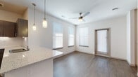 This single-floor residence offers a clean, modern aesthetic throughout, combining thoughtful design with practical finishes. The open-concept living and dining area features warm hardwood-style flooring, a ceiling fan with light fixture, and multiple windows fitted with white horizontal blinds that allow ample natural light to fill the space. A private exterior door adds convenience and accessibility directly from the living area.

The kitchen is a standout feature, equipped with dark espresso cabinetry, granite-look countertops, a classic white subway tile backsplash, and a full suite of stainless steel appliances including a refrigerator and electric range. Pendant lighting over the kitchen counter adds a contemporary touch, while recessed ceiling lights provide functional illumination.

The bedrooms are carpeted for comfort, each featuring ceiling fans, generous windows with blinds, and built-in closets with double hanging rods for organized storage. The hallway and common areas continue the hardwood-style flooring, maintaining a cohesive look throughout.

The bathrooms are finished with dark wood vanities, granite-topped sinks, framed mirrors, overhead cabinetry, wood-look flooring, and tiled tub-shower combinations, offering a clean and functional design. Overall, this space presents a well-balanced blend of modern style and everyday functionality.