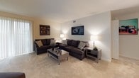 This single-floor residence offers a thoughtfully organized layout across several well-defined living spaces. The living room is generously sized, featuring plush wall-to-wall carpeting, neutral-toned walls, and large sliding glass doors dressed with vertical blinds that allow abundant natural light to fill the space. The open layout comfortably accommodates multiple seating arrangements, making it well-suited for both relaxing and entertaining.

Adjacent to the living area, the dining room continues the carpeted flooring and features a sliding glass door with vertical blinds, providing additional natural light. An elegant chandelier serves as a focal point overhead, adding a refined touch to the space.

The galley-style kitchen is efficiently designed, featuring light wood cabinetry, dark granite-style countertops, and black appliances including a gas range, refrigerator, and built-in microwave. Light vinyl flooring runs the length of the kitchen, complementing the cabinetry.

The bedrooms are comfortably sized, each with carpeted flooring, windows with blinds, and closets offering practical storage. The bathroom includes a tub-shower combination, tiled walls, a window for natural ventilation, and a clean white vanity, delivering a functional and straightforward design.