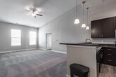Located at 304 Lightfoot Rd in Williamsburg, VA, this single-floor residence offers a well-designed layout with a variety of functional spaces. The open-concept living area immediately stands out with its dramatically vaulted ceilings and ceiling fan, creating an airy, expansive atmosphere. Plush neutral carpeting flows throughout the living and bedroom areas, while natural light enters through multiple windows fitted with blinds.

The kitchen features dark espresso cabinetry contrasted by granite-style countertops and a full suite of stainless steel appliances, including a refrigerator, range, and microwave. Light wood-tone flooring anchors the kitchen's contemporary aesthetic, and a nearby pantry with wire shelving provides ample storage.

The bedrooms are generously sized, each carpeted and equipped with ceiling fans. One bedroom includes a walk-in closet and direct access to a bathroom. Bathrooms are finished with tile flooring and dark vanity cabinetry; one includes a tub-shower combination, while another features a glass-enclosed tiled walk-in shower with brushed nickel fixtures.

A dedicated laundry area houses a full-size GE washer and dryer with overhead wire shelving. Overall, the space presents a clean, neutral palette with practical finishes throughout.
