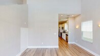 Located at 154 Promenade Pl in Brunswick, Georgia, this two-story home offers a thoughtfully designed layout spread across two floors. The exterior showcases classic coastal cottage-style architecture with light-colored siding, a covered front porch, and well-maintained landscaping — set within a welcoming residential community surrounded by lush green lawns.

The main floor serves as the primary living area, featuring a combined kitchen and living room, an entrance, and garage access. The kitchen is equipped with white shaker-style cabinetry, granite countertops, a subway tile backsplash, stainless steel appliances including a range, microwave, and dishwasher, and a double-basin sink beneath a bright window. Light wood-tone flooring flows throughout, creating a clean, cohesive look.

The bedrooms are finished with the same warm hardwood-style flooring, neutral gray walls, crown molding, and ceiling fans. The generously sized primary bedroom offers a comfortable retreat. Bathrooms include both tub/shower combos with tile surrounds and a glass-enclosed walk-in shower, finished with tile flooring and granite vanities. The backyard features a private green space bordered by mature trees, offering a natural, secluded setting.
