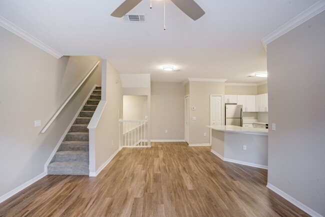 Image of the living room area with wood-style plank style floors a staircase leading upstairs. - Amara at Metro West