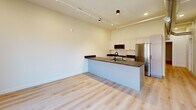 Located on the third floor of a historic building in downtown Kalamazoo, this one-bedroom, one-bathroom unit masterfully blends industrial character with contemporary design. Light hardwood flooring runs throughout, complementing the crisp white walls and clean, modern aesthetic.

The open-concept living, dining, and kitchen area serves as the heart of the unit. A large picture window frames striking views of the surrounding downtown architecture, flooding the space with natural light. The kitchen is well-appointed with dark granite countertops, white shaker-style cabinetry, black hardware accents, stainless steel appliances — including a full-size refrigerator and range — and a dedicated pantry for additional storage. Track lighting overhead adds a modern industrial touch.

A hallway connects the main living area to the private bedroom, which features a dedicated closet and a dramatic exposed brick accent wall that speaks to the building's rich history. The bathroom continues the heritage aesthetic with its own exposed brick wall, complemented by granite counters and modern fixtures. Notably, the bathroom also houses an in-unit washer for added convenience. The entry hallway showcases exposed ductwork, reinforcing the loft-inspired character of the space throughout.