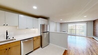 Located at 78 Laning St in Southington, CT, this two-bedroom, one-bathroom residence offers a well-designed single-floor layout with thoughtful updates throughout. The open kitchen and living area serve as the heart of the home, where the kitchen features a clean, modern aesthetic with white upper cabinetry, warm wood lower cabinets, white countertops, and a full suite of stainless steel appliances including a refrigerator, dishwasher, range, and microwave. The living room makes a striking impression with its full-length exposed brick accent wall, gleaming hardwood floors, recessed lighting, and a sliding glass door with vertical blinds that invites abundant natural light and outdoor views. Both bedrooms continue the warm hardwood flooring, are illuminated by recessed lighting, and are served by windows overlooking lush greenery. The primary bedroom is generously sized and includes a dedicated closet. The bathroom is neatly appointed with large-format tile flooring, a light wood vanity with a white countertop, a framed mirror, and matte black fixtures that add a contemporary touch. Baseboard heating is present throughout, and a wall unit provides additional climate control in the living and bedroom areas.
