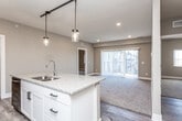 This single-floor residence offers a thoughtfully designed open-concept layout where the kitchen and living area flow seamlessly together. The kitchen serves as a functional centerpiece, featuring white shaker cabinetry, granite countertops, stainless steel appliances including an electric range, microwave, and refrigerator, and a kitchen island with a double sink. Pendant lights on a track rail hang above the island, complementing recessed lighting throughout. Wood-look hard flooring runs through the kitchen and entry areas, transitioning to plush carpet in the living room and bedrooms.

The living area is generously proportioned, with neutral-toned walls and a sliding glass door that invites natural light and provides outdoor access. Bedrooms are carpeted and well-sized, each offering closet storage, including a spacious walk-in closet with multi-level shelving and hanging rods. The unit includes two full bathrooms, both finished with granite-topped white vanities and wood-look flooring. The primary bathroom features a tub-shower combination, while the secondary bathroom offers a walk-in shower. The overall aesthetic is clean, modern, and move-in ready.