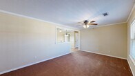 Located at 2103 Beacon Ridge Way in Van Buren, Arkansas, this single-floor home offers a comfortable and functional layout with consistent warm, neutral tones throughout. The living area is generously proportioned, featuring plush carpeting, crown molding, a ceiling fan with light fixture, and a pass-through opening that connects to the kitchen, enhancing the sense of openness between spaces. Natural light filters in through windows fitted with blinds, adding brightness to the carpeted rooms.

The kitchen is well-equipped and thoughtfully designed, showcasing rich wood cabinetry, a tile backsplash, white appliances including a range, microwave, dishwasher, and refrigerator, along with wood-look flooring and elegant pendant and chandelier lighting. Crown molding adds a refined touch to the kitchen as well.

The bedrooms are comfortably sized, each outfitted with ceiling fans, plush carpeting, and natural light from windows. One bedroom includes a closet with double doors, providing ample storage.

The bathrooms continue the warm aesthetic with wood-look flooring, rich wood vanity cabinetry, white countertops, and framed mirrors. Each bathroom is clean and functional in design.

Throughout the home, consistent finishes—including white trim, warm beige walls, and wood-look flooring in wet areas—create a cohesive and inviting atmosphere.
